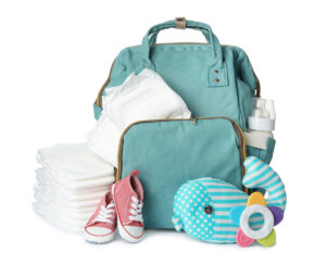 Teal diaper bag with baby essentials including diapers, bottle, shoes, and toys on a white background.
